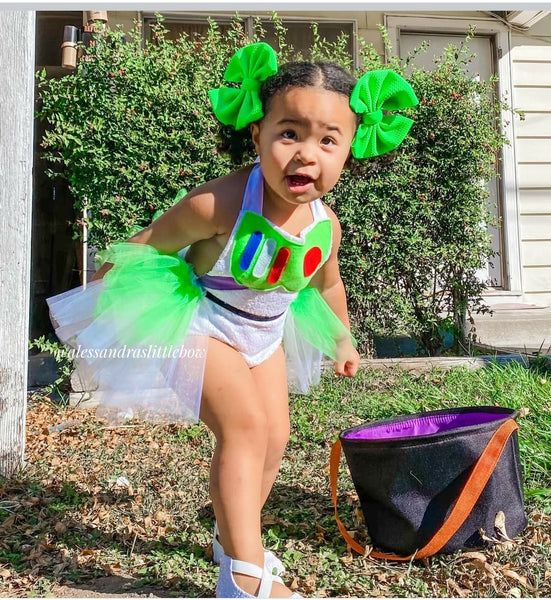 Child in a Buzz Lightyear costume with green hair bows outdoors.