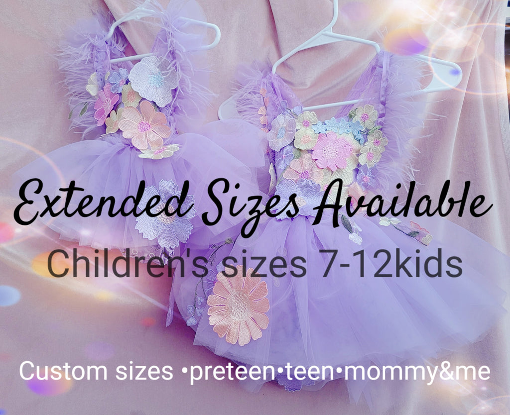 A promotional graphic showing two lavender tulle tutus with floral appliqués hanging on white hangers against a soft pink fabric backdrop. Large overlaid text reads 'Extended Sizes Available' and 'Children's sizes 7-12kids', with smaller text at the bottom mentioning custom sizes for preteen, teen, mommy & me.