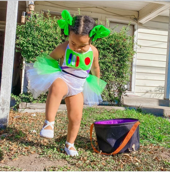 Child in Buzz Lightyear costume with a Halloween bucket outdoors.