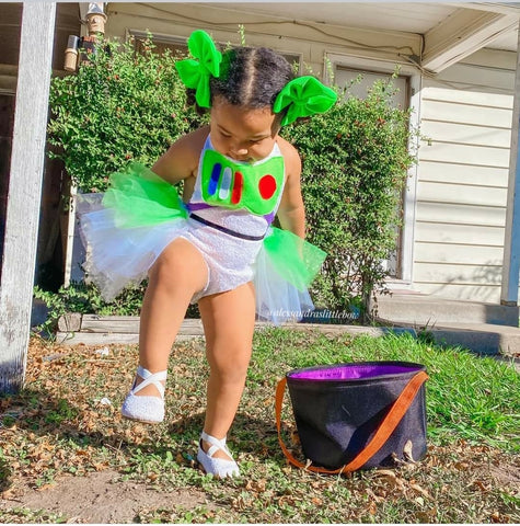 Child in Buzz Lightyear costume with a Halloween bucket outdoors.